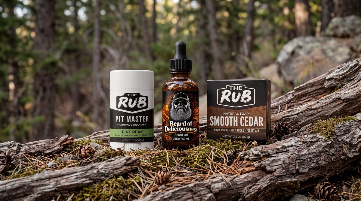 Beard of Deliciousness Basic Bundle featuring Matt Ramsey's beard oil, The Rub Pit Master Pine Peak deodorant, and Smooth Cedar natural soap in a rugged forest setting.