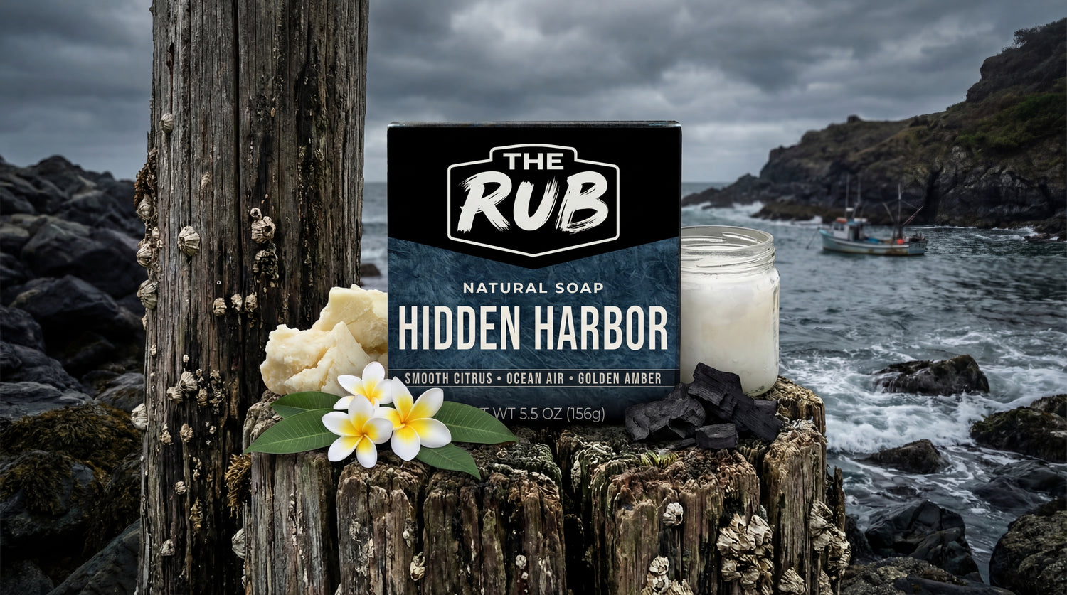 Hidden Harbor natural bar soap by The Rub on weathered ocean pylons with tropical flowers, charcoal, and a rocky coast.