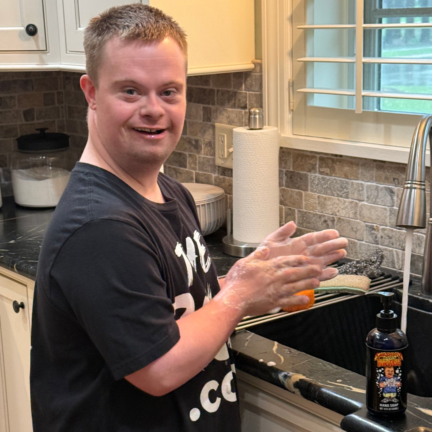 Drew, from @down.rightdelicious, smiles broadly while washing his hands at the sink using his custom, exclusive