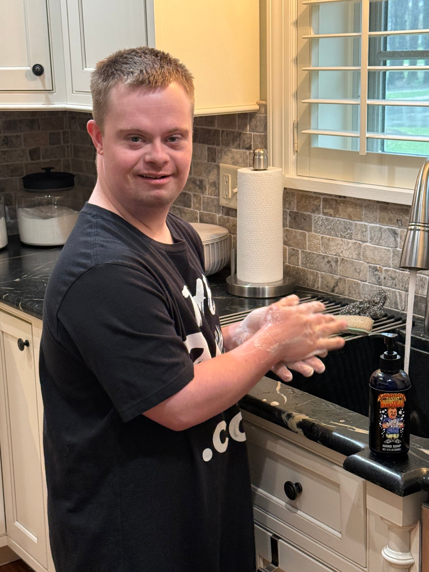Drew, from @down.rightdelicious, smiles broadly while washing his hands at the sink using his custom, exclusive 