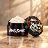 The Rub Tobacco Vanilla Beard Butter in an open amber jar with the lid beside it, shown on a premium warm-toned surface with a soft studio background.