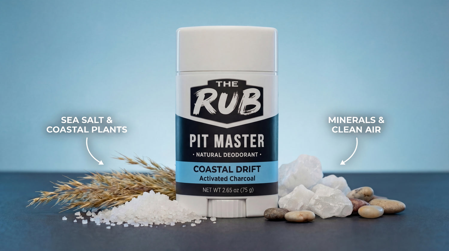 Coastal Drift natural deodorant stick surrounded by sea salt, coastal grass, and white minerals on a blue background.