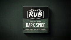 Dark Spice natural soap box by The Rub, highlighting ingredients like woods, citrus, shea butter, and coconut on a dark background.