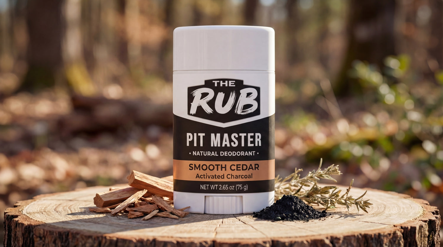 The Rub Smooth Cedar natural deodorant on a forest tree stump surrounded by cedar chips, rosemary, and charcoal.