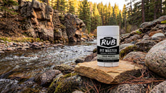 True North unscented natural deodorant stick displayed outdoors resting on a flat rock beside a rocky mountain river.